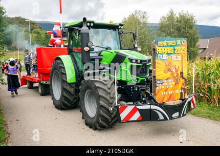 Les villageois vêtus de costumes traditionnels participent fièrement à la parade annuelle des vaches alpines dans le village de Lignières, dans les montagnes du Jura, en Suisse. Banque D'Images