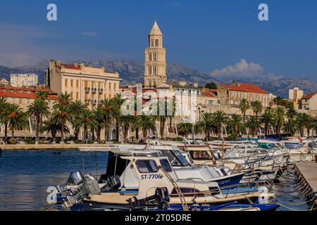 paysage du port de split avec une rangée de petits bateaux devant la promenade bordée d'arbres et la vieille ville historique avec un clocher proéminent Banque D'Images