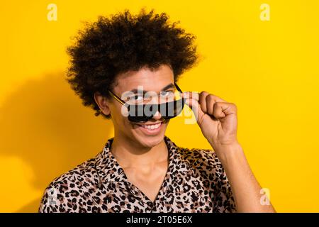 Portrait de la belle personne positive avec chevelure Wear chemise doigts de léopard touchant le sourire de lunettes de soleil isolé sur fond de couleur jaune Banque D'Images