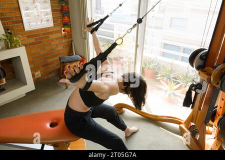 vue de dessus d'une femme caucasienne méconnaissable, avec l'épaule et le dos d'entraînement à bras ouverts à la maison avec machine d'exercice, élongand et renforcement supérieur Banque D'Images