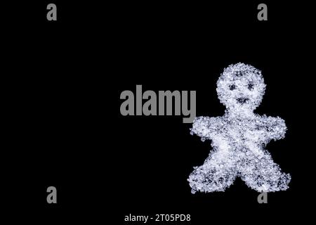 Silhouette d'un homme de Noël fait de sel comme neige sur fond noir, espace copie. Carte de voeux créative d'hiver maison Banque D'Images