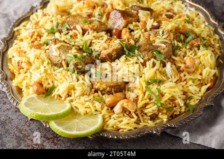 Festif pilaf Kacchi mouton Biryani avec des noix, des raisins secs, oignons frits gros plan sur l'assiette sur la table. Horizontal Banque D'Images