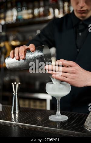 vue rognée du barman avec shaker à cocktail faisant du punch au lait dans le bar, cocktail artistique Banque D'Images