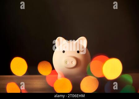 Tirelire entourée de lumières colorées floues. Concepts : économies sur les achats de vacances, à l'achat de cadeaux de noël. Banque D'Images