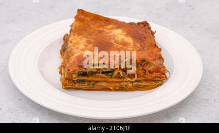 Lasagnes aux épinards.Délicieux lasagnes aux épinards servies avec du romarin frais sur une assiette sur fond gris clair Banque D'Images