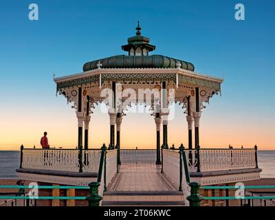 Pavillon victorien Bandstand sur le front de mer au coucher du soleil avec une seule personne dans la contemplation tranquille Brighton City East Sussex Angleterre Banque D'Images