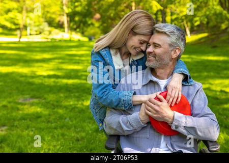 Mignon couple se serrant les uns les autres et regardant heureux dans le parc Banque D'Images