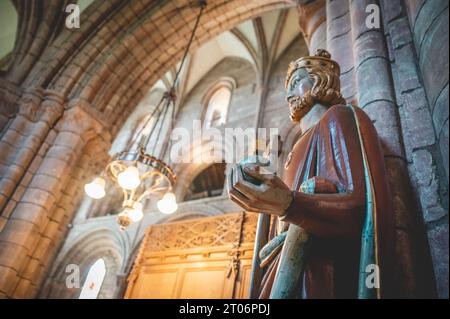 Roi tenant une pomme riche, une hache et une croix, à l'intérieur de la cathédrale St Magnus, vue latérale à faible angle, lustre illuminé, Kirkwall, Écosse Banque D'Images