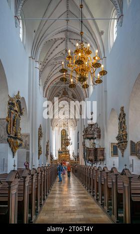 À l'intérieur, à la cathédrale d'Aarhus, lustre illuminé suspendu au toit, bancs en bois, couloir, touriste en arrière-plan, plan vertical, D. Banque D'Images