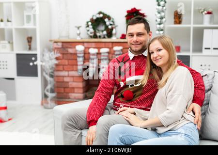 Un couple est assis sur un canapé dans une pièce décorée avec des ornements de Noël Banque D'Images