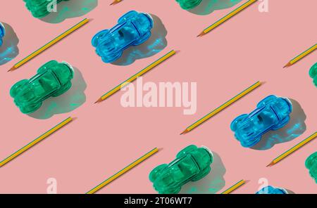 Motif de voitures de course à la mode fait de crayons et taille-crayons sur fond rose pastel avec espace de copie. Concept scolaire minimal. Banque D'Images