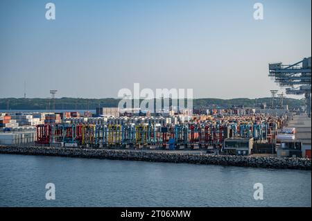 Exportation importation conteneur maritime au port d'Aarhus, Danemark, grues et véhicule industriel avec mer en face, dans la soirée Banque D'Images