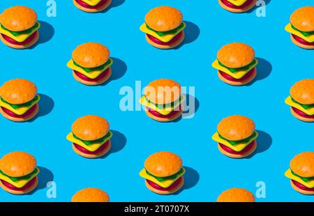 Composition créative de motif de grand hamburger fait de bonbons gélifiés colorés sur fond bleu. Concept alimentaire minimal. Idée savoureuse de bonbons de gelée. Banque D'Images