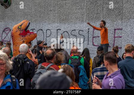 La Haye, Hollande du Sud, pays-Bas. 4 octobre 2023. Un organisateur du blocus A12 parle et motive un grand groupe de militants pour le climat, dont l'un portait un costume de dinosaure. Extinction les militants de la rébellion bloquent l'autoroute A12 à la Haye, aux pays-Bas. (Image de crédit : © James Petermeier/ZUMA Press Wire) USAGE ÉDITORIAL SEULEMENT! Non destiné à UN USAGE commercial ! Banque D'Images