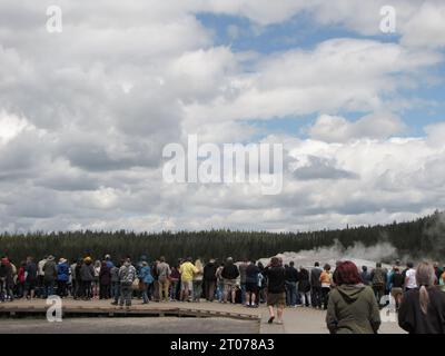 Les touristes se sont rassemblés sur la promenade dans le parc national de Yellowstone en regardant le geyser et en écoutant l'éducation des gardes du parc. Banque D'Images