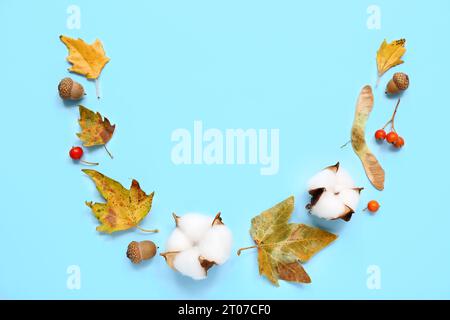 Belles feuilles d'automne avec des fleurs de coton, des glands et des baies de viburnum sur fond bleu Banque D'Images