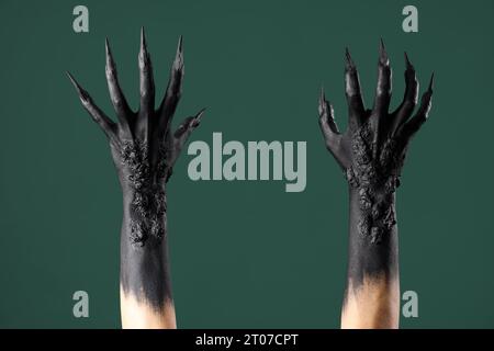 Mains noires de sorcière avec des griffes sur fond vert. Fête d'Halloween Banque D'Images