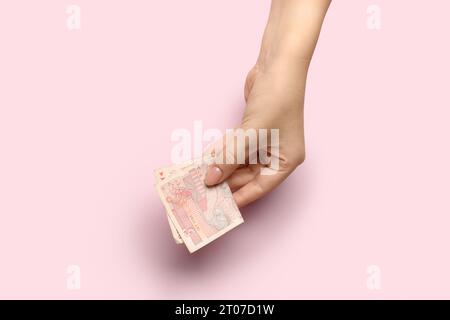Main féminine tenant le billet de banque de lev bulgare sur fond rose Banque D'Images