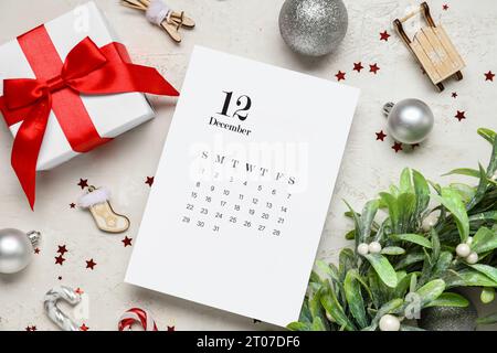 Calendrier papier pour décembre 12, boîte cadeau et décorations de Noël sur fond blanc Banque D'Images