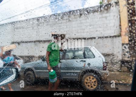 Valenca, Bahia, Brésil - 9 janvier 2023 : des gens marchent dans la rue avec des parapluies un jour de pluie dans la ville de Valenca, Bahia. Banque D'Images