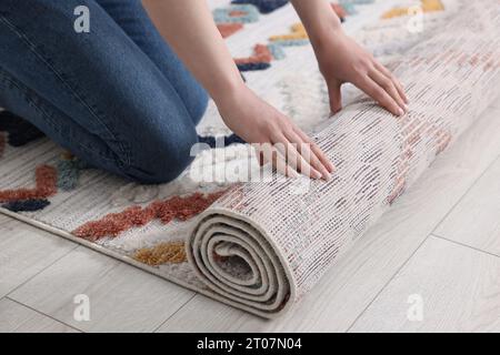 Femme déroulant tapis avec beau motif sur le sol dans la chambre, closeup Banque D'Images