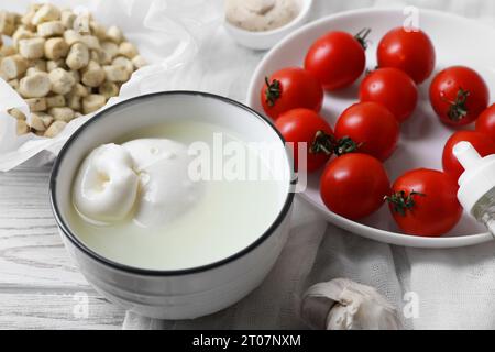 Délicieux fromage burrata servi avec croûtons et tomates sur table en bois blanc, gros plan Banque D'Images