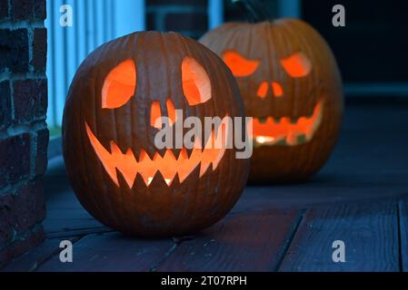 Des citrouilles sculptées brillent sur le porche avant d'une maison pendant l'Halloween. Banque D'Images