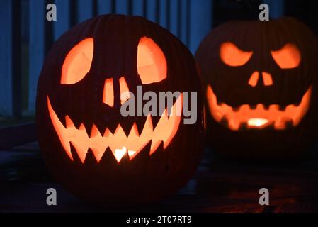 Des citrouilles sculptées brillent sur le porche avant d'une maison pendant l'Halloween. Banque D'Images