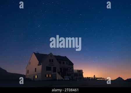 Une maison juste après le coucher du soleil avec des étoiles brillantes au-dessus et une lueur orange Banque D'Images