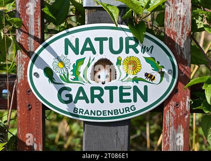 Alt Galow, Allemagne. 19 septembre 2023. Un panneau sur la clôture du jardin indiquant 'Natur im Garten Brandenburg' par Marina Delzer, guide de la nature et du paysage. Les jardins devraient avoir l'air bien entretenus, la pelouse taillée. Et ils devraient faire le moins de travail possible. Ce point de vue est encore largement répandu. Dans l'intérêt de la biodiversité, il existe cependant des initiatives et des associations pour des jardins quasi naturels dans lesquels les coins sauvages deviennent un paradis pour les animaux. (À dpa: "Nature sauvage ou jardin? La tendance est aux jardins naturels verts et sauvages ») crédit : Patrick Pleul/dpa/Alamy Live News Banque D'Images