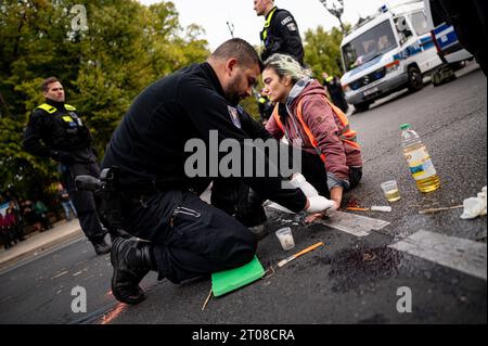 Berlin, Allemagne. 05 octobre 2023. Les membres de la dernière génération sont restés dans la rue du 17 juin devant la porte de Brandebourg. Les militants pour le climat de la dernière génération avaient de nouveau mis en place des barrages routiers à plusieurs endroits à Berlin jeudi matin, y compris à la porte de Brandebourg. Crédit : Fabian Sommer/dpa/Alamy Live News Banque D'Images