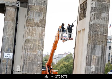 Berlin, Allemagne. 05 octobre 2023. Les employés d'un restaurateur peignent sur des taches de peinture provenant d'une manifestation précédente de la "dernière génération" à la porte de Brandebourg. Crédit : Fabian Sommer/dpa/Alamy Live News Banque D'Images