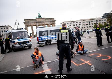 Berlin, Allemagne. 05 octobre 2023. Les membres de la dernière génération sont restés dans la rue du 17 juin devant la porte de Brandebourg. Les militants pour le climat de la dernière génération avaient de nouveau mis en place des barrages routiers à plusieurs endroits à Berlin jeudi matin, y compris à la porte de Brandebourg. Crédit : Fabian Sommer/dpa/Alamy Live News Banque D'Images