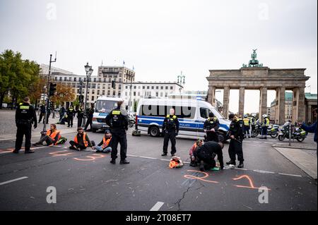 Berlin, Allemagne. 05 octobre 2023. Les membres de la dernière génération sont restés dans la rue du 17 juin devant la porte de Brandebourg. Les militants pour le climat de la dernière génération avaient de nouveau mis en place des barrages routiers à plusieurs endroits à Berlin jeudi matin, y compris à la porte de Brandebourg. Crédit : Fabian Sommer/dpa/Alamy Live News Banque D'Images