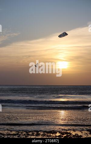 un professionnel du kitesurf au milieu d'un grand saut faisant des tours de mi-vol à tarifa espagne Banque D'Images