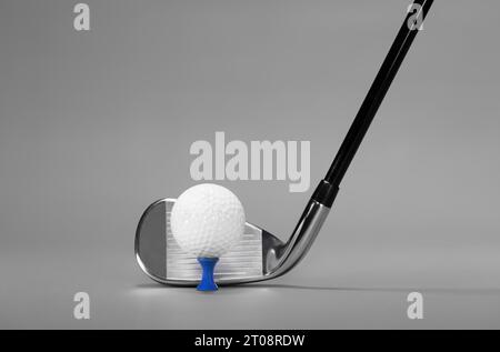 Club de golf fer et balle sur un tee-shirt bleu, photographié sur un fond gris luxuriant avec Copy Space Banque D'Images