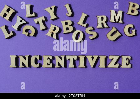 Incentivize, mot en lettres de l'alphabet en bois isolé sur fond violet comme titre de bannière Banque D'Images