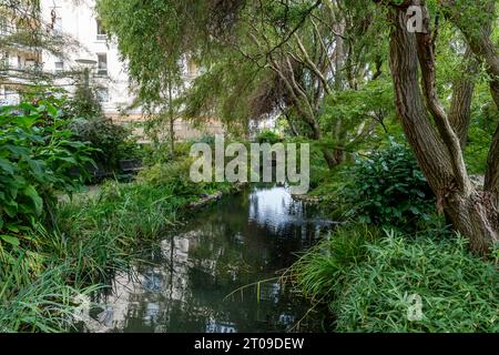 Vue sur le cours de la rivière Bièvre coulant brièvement en plein air dans la ville de Cachan, France Banque D'Images