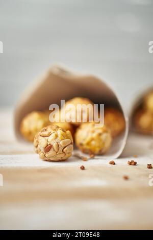 Panellets doux dans des cônes de papier journal placés sur une table en bois contre un mur blanc flou Banque D'Images