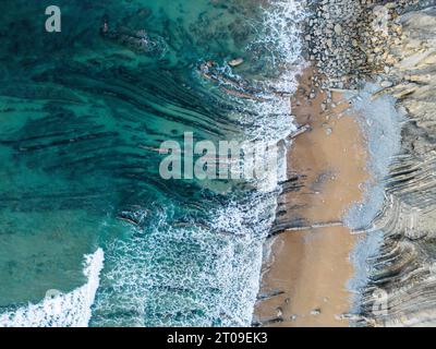 Vue aérienne de vagues mousseuses turquoise lavant une plage de sable au pays Basque lors d'une journée ensoleillée d'été Banque D'Images