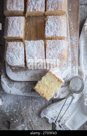 Vue de dessus de la planche de bois avec gâteau Pasiego un gâteau typique de Catalogne en Espagne saupoudré de sucre sur une table en bois rustique Banque D'Images
