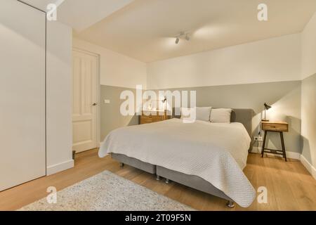 Intérieur de la chambre éclairée avec lit blanc entouré de murs blancs dans un appartement spacieux moderne Banque D'Images