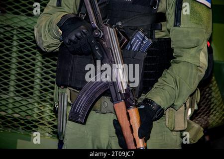 Soldat lourdement équipé en uniforme de camouflage, membre de forces spéciales pour les opérations antiterroristes et les combats rapprochés en guerre, tenant une arme à feu Banque D'Images