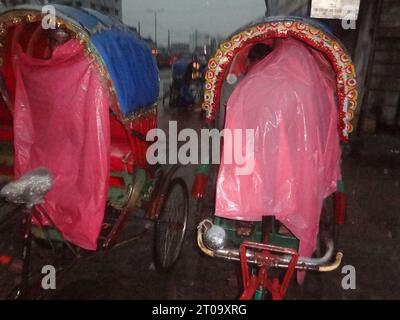 Dhaka, Bangladesh. 5 octobre 2023. Lorsqu’ils se réfugient sur leur pousse-pousse à Dhaka, les tireurs de pousse-pousse utilisent une feuille de plastique pour se protéger de la pluie. La vie quotidienne de la capitale aurait été perturbée par une dépression pluviale continue. (Image de crédit : © MD Mehedi Hasan/ZUMA Press Wire) USAGE ÉDITORIAL SEULEMENT! Non destiné à UN USAGE commercial ! Banque D'Images