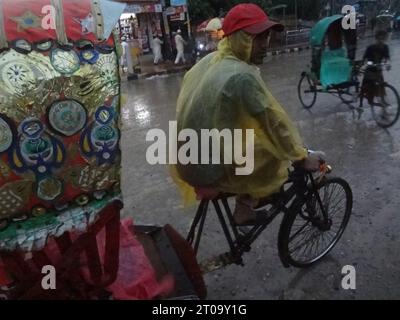 Dhaka, Bangladesh. 5 octobre 2023. Un tire-pousse attend les passagers tout en utilisant une feuille de plastique pour les protéger de la pluie. La vie quotidienne de la capitale aurait été perturbée par une dépression pluviale continue. (Image de crédit : © MD Mehedi Hasan/ZUMA Press Wire) USAGE ÉDITORIAL SEULEMENT! Non destiné à UN USAGE commercial ! Banque D'Images