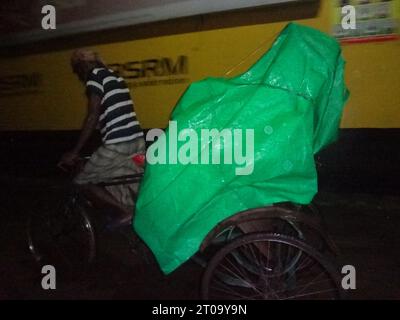 Dhaka, Bangladesh. 5 octobre 2023. Un tireur de pousse-pousse recouvre ses marchandises d'une feuille de plastique pour le protéger de la pluie à Dhaka. La vie quotidienne de la capitale aurait été perturbée par une dépression pluviale continue. (Image de crédit : © MD Mehedi Hasan/ZUMA Press Wire) USAGE ÉDITORIAL SEULEMENT! Non destiné à UN USAGE commercial ! Banque D'Images