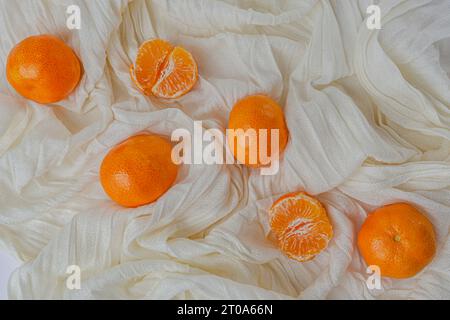 Les mandarines fraîches sont situées sur un fond de tissu blanc. Photo de haute qualité Banque D'Images