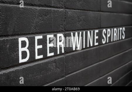 Bière, vin et spiritueux peints sur mur noir. Grandes lettres blanches sur noir. Boisson alcoolisée ou publicité pour boisson. Pub, bar, restaurant ou vin St Banque D'Images