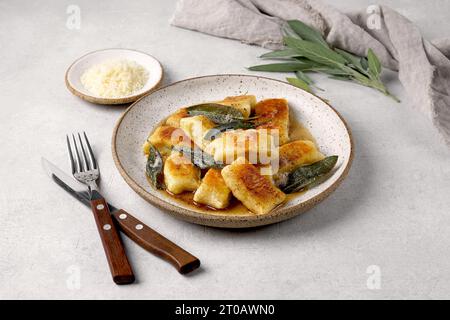 Gnocchi maison italien avec pommes de terre, fromage et beurre de sauge, servi dans une assiette sur une table lumineuse. Cuisine italienne. Espace de copie. Banque D'Images