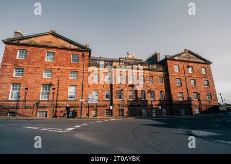 Dunbar, East Lothian , écosse - 13 août 2023 vue générale de Sunlit High Street avec des bâtiments peints et des pots de fleurs en fleurs en premier plan. Bonjour Banque D'Images